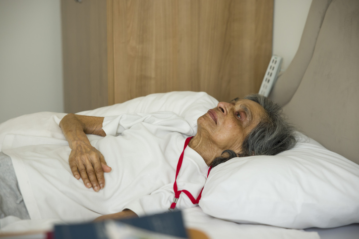 leżąca w łóżku starsza chora kobieta